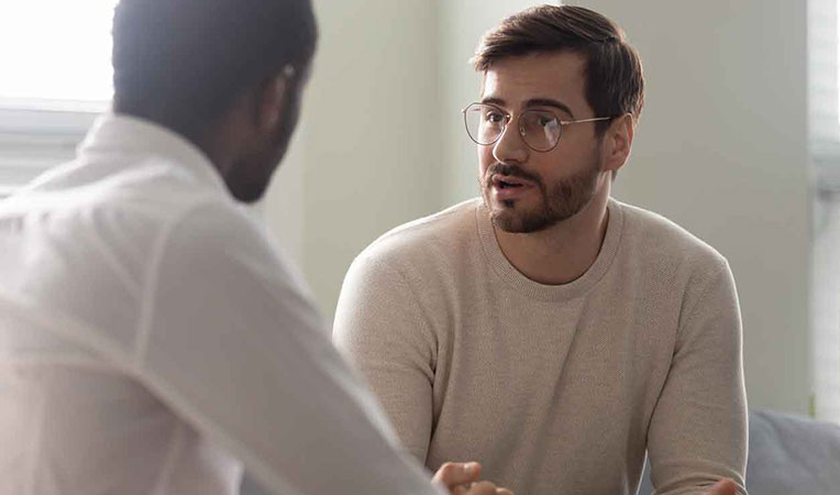 Two men talking; one appears to be assisting the other, representing SLB employee support.